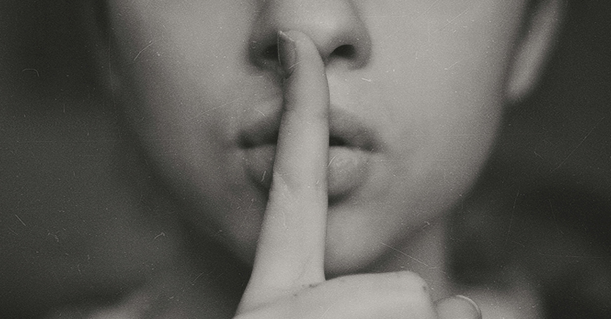 A woman holding one finger to her lips